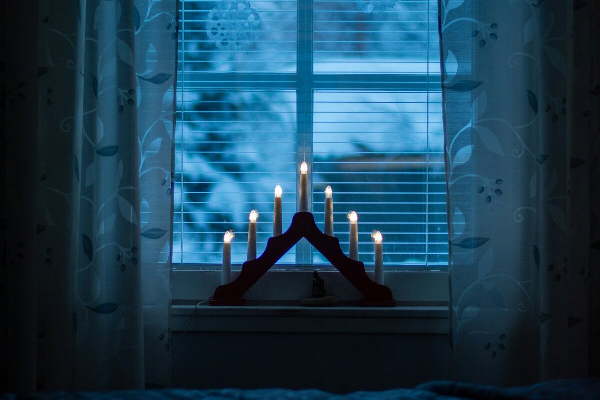 Sinivalkoiset kynttilät ikkunalla