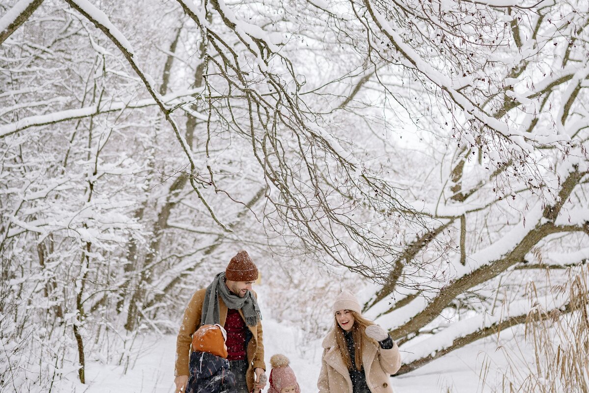 Perhe talviretkellä lumisessa metsässä